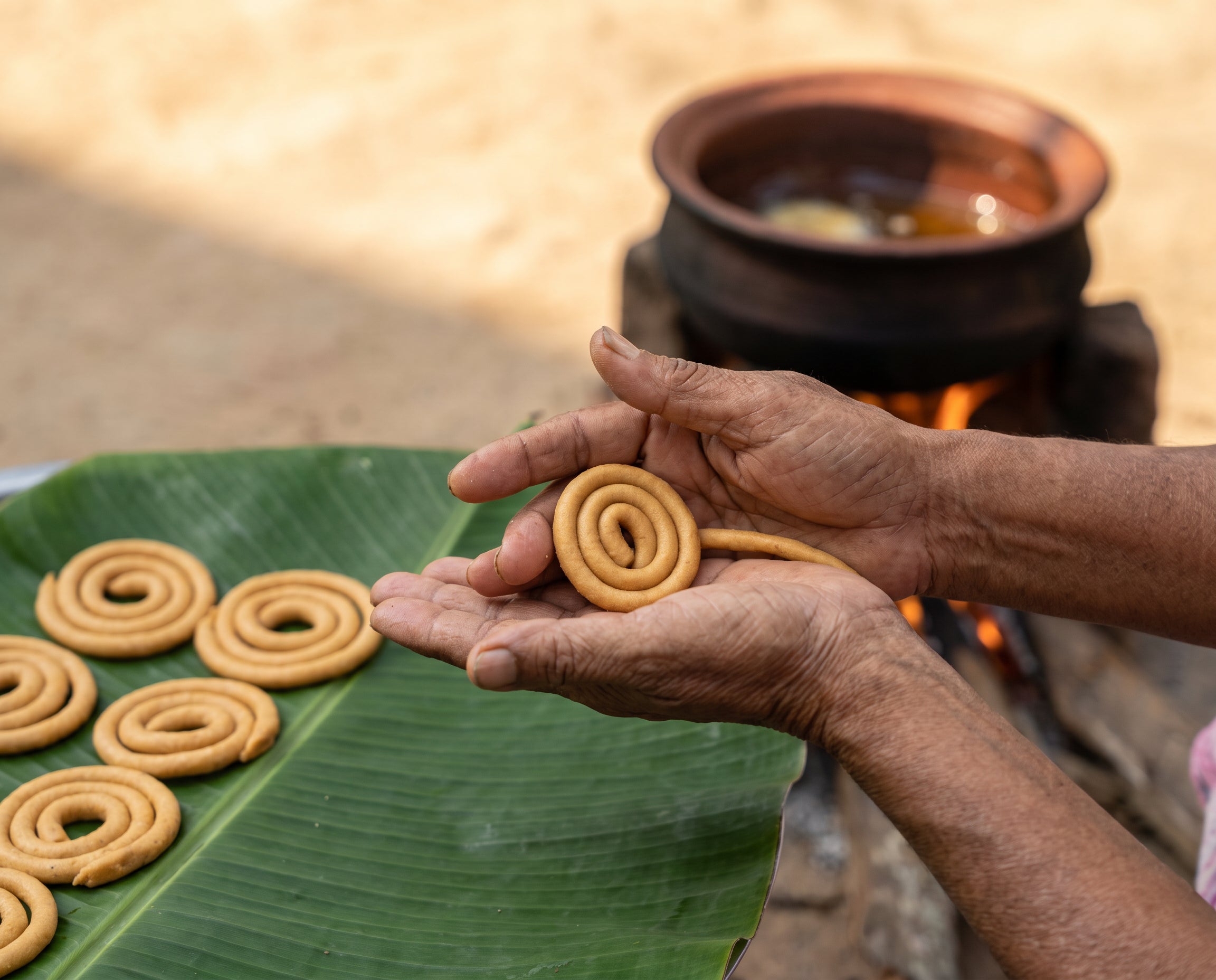 Hands rolling sakinalu dough into spirals, the traditional way
